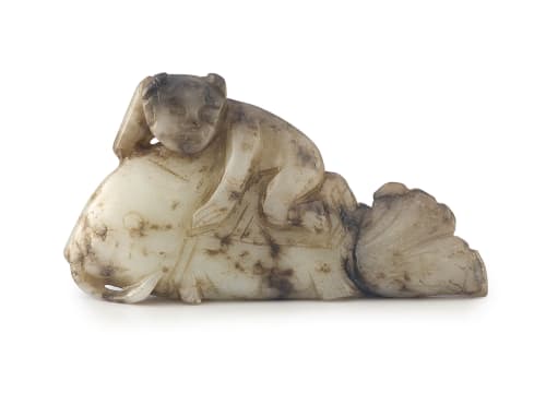A Chinese mottled grey and white jade carving of a small boy astride a fish, Qing Dynasty, 19th/20th century