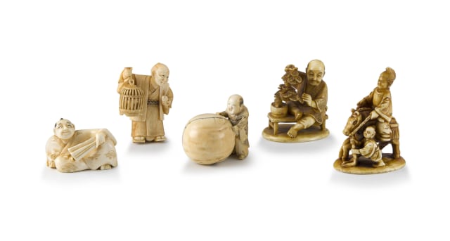 A Japanese ivory netsuke of a figure pushing a snowball, Meiji period, 1868-1912