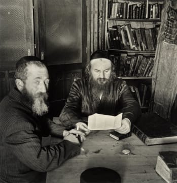 Roman Vishniac; Rabbi Leibel Eisenberg (Reading) and His Shammes. Lask, 1936