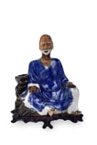 A Japanese ceramic seated figure on wooden base, late 19th or early 20th century