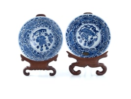A pair of Chinese blue and white porcelain rice bowls on rosewood stands, Kangxi period, 1662-1722