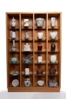 Various Artists; Wooden cabinet with glass shelves and fluorescent lights with 24 ceramic art pieces